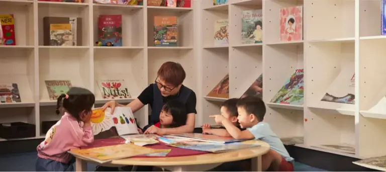 Children and an educator exploring learning materials together at a table.