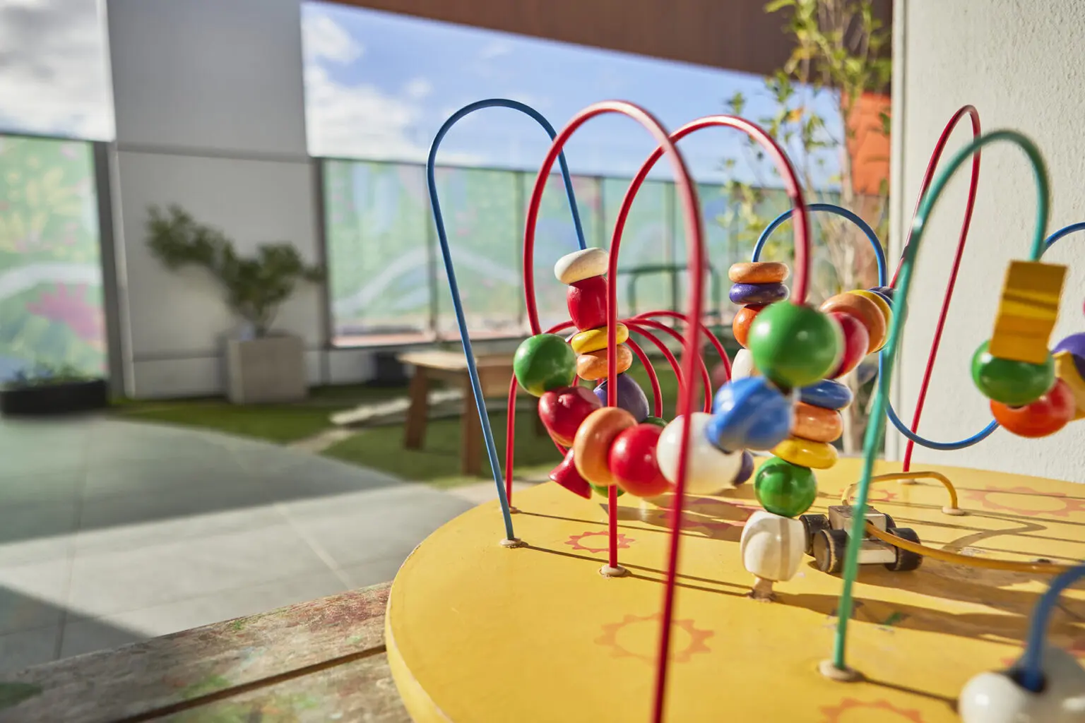 A wooden bead maze with colourful beads and looping wires.